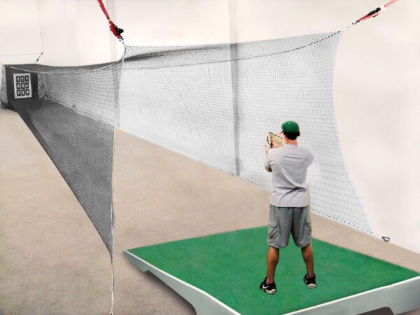A man is swinging at a ball on the ground.