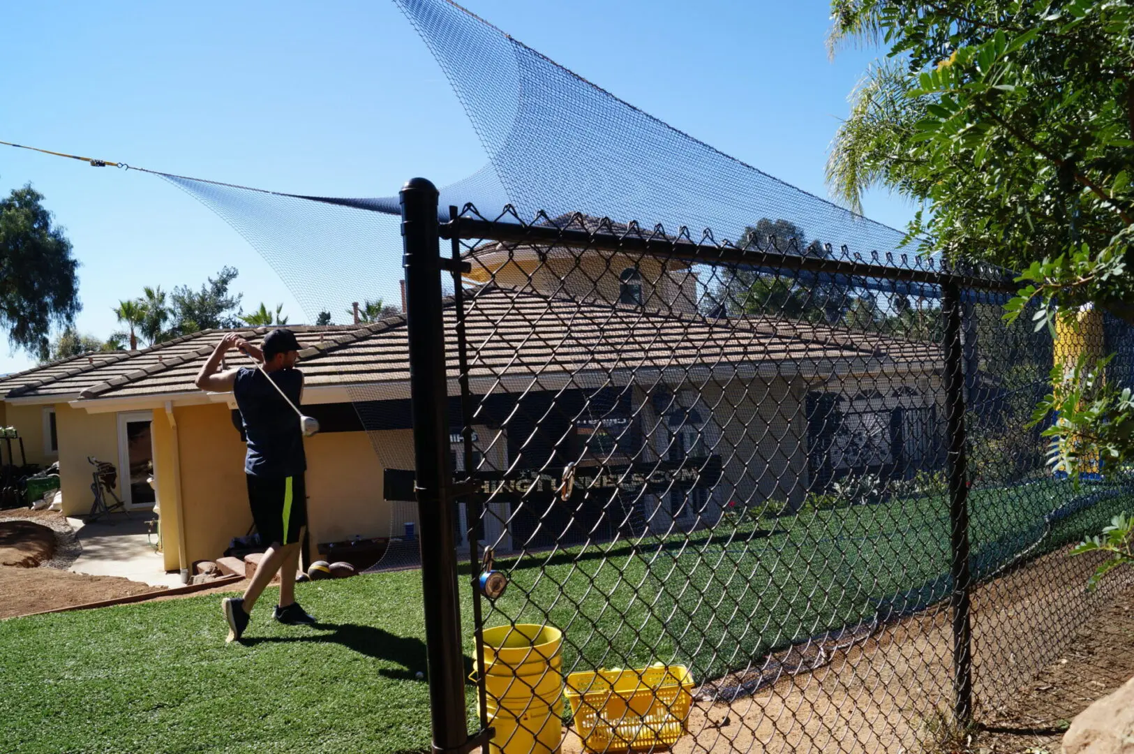 A person standing in front of a fence with a bat.