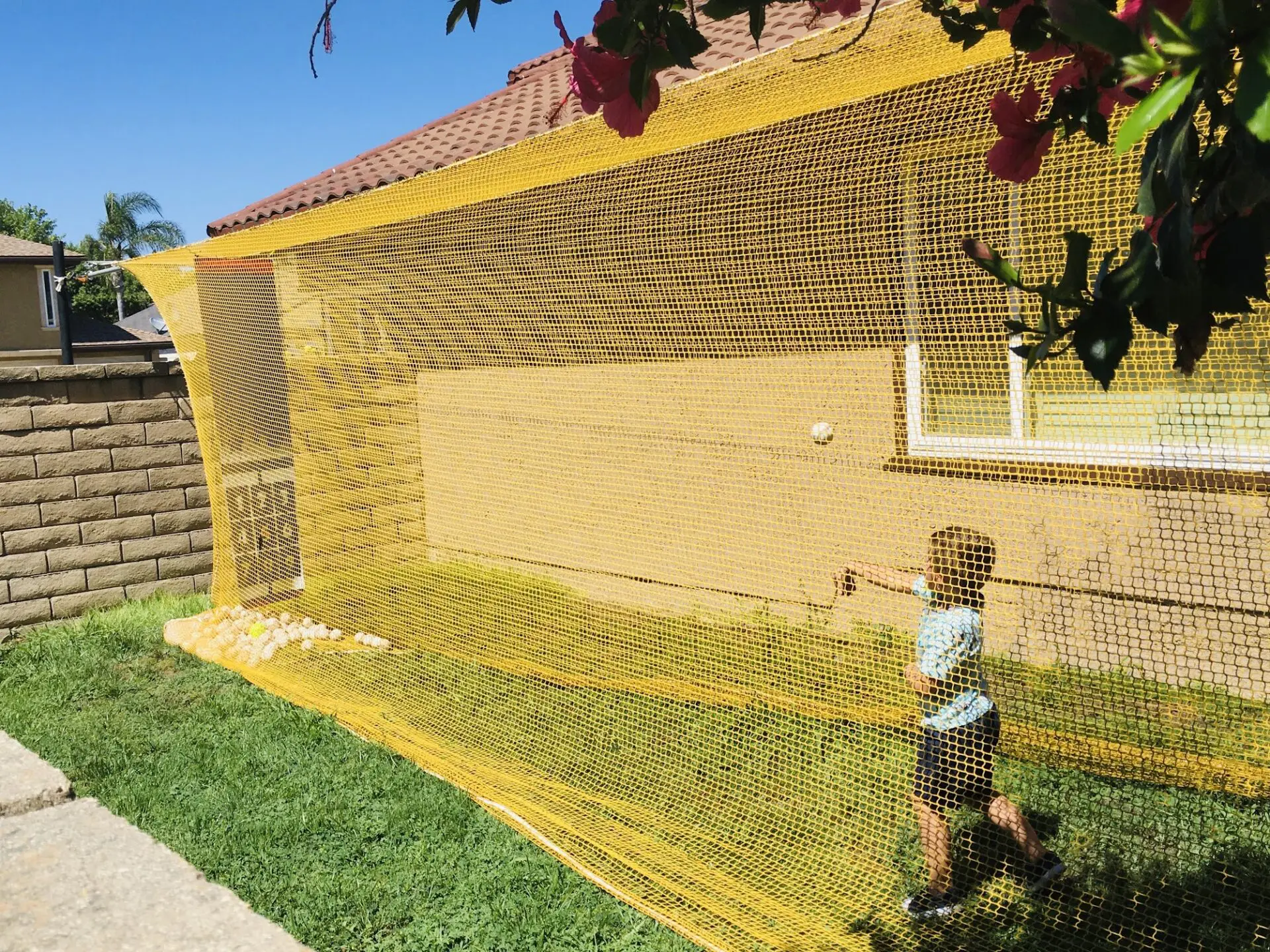 A young boy is playing baseball in the yard.