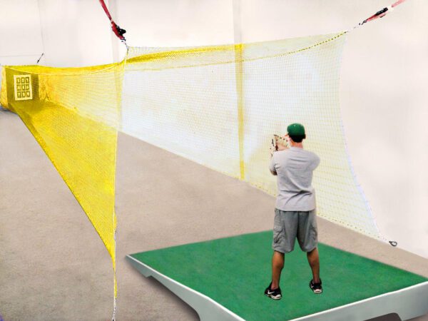 A man is standing on the ground in front of a net.