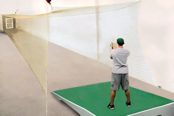 A man is swinging at a ball on the batting cage.
